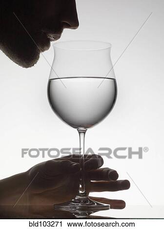 Stock Image - Man drinking water from wine glass. Fotosearch
