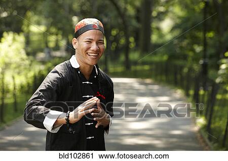Stock Image - Man in traditional Asian clothing in grass. Fotosearch
