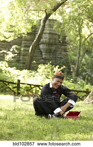 Man in traditional Asian clothing sitting in grass View Large Photo Image Stock Photo - Man in traditional Asian clothing sitting in grass. Fotosearch