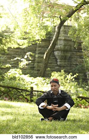 Man in traditional Asian clothing sitting in grass View Large Photo Image Stock Photograph - Man in traditional Asian clothing sitting in grass. Fotosearch
