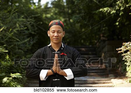 Stock Photography - Man in traditional Asian clothing praying. Fotosearch