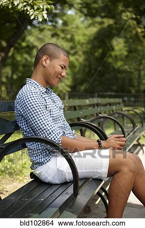 Picture - Man using digital tablet on park bench. Fotosearch