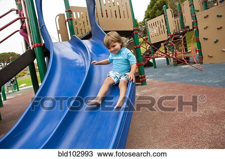 Mixed race boy sliding down slide on playground View Large Photo Image Stock Image - Mixed race boy sliding down slide on playground. Fotosearch