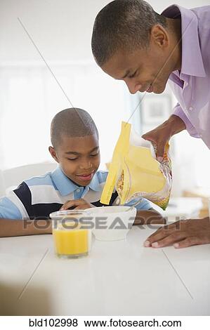 Mixed race man pouring cereal for son View Large Photo Image Stock Photo - Mixed race man pouring cereal for son. Fotosearch