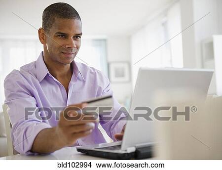 Picture - Mixed race man shopping online with credit card. Fotosearch