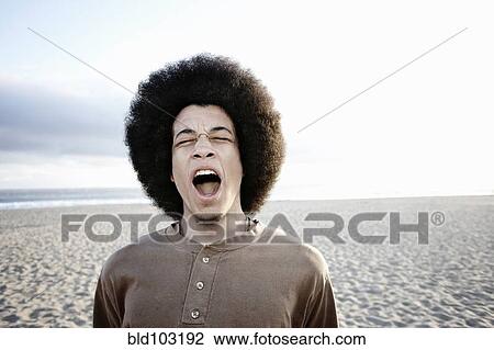 Stock Image - Mixed race man shouting on beach. Fotosearch
