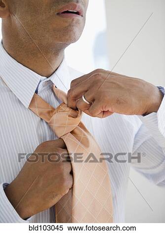 Mixed race man tying necktie View Large Photo Image Stock Photography - Mixed race man tying necktie. Fotosearch