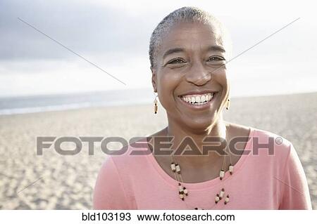 Stock Image - Smiling Black woman on beach. Fotosearch
