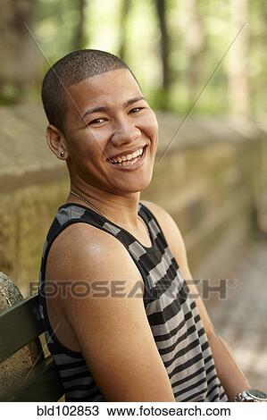 Stock Image - Smiling man sitting on bench outdoors. Fotosearch