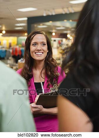 Stock Image - Woman talking to customers in store. Fotosearch