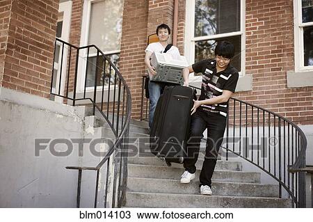 Stock Image - Asian men with luggage waking down stairs. Fotosearch