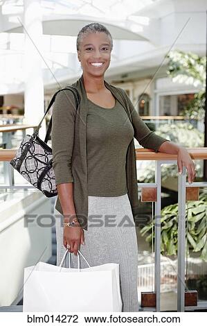 Black woman holding shopping bags in mall View Large Photo Image Stock Image - Black woman holding shopping bags in mall. Fotosearch