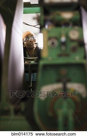 Stock Photography - Black worker using factory machinery. Fotosearch