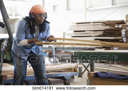 Black worker working with lumber in factory View Large Photo Image Stock Image - Black worker working with lumber in factory. Fotosearch