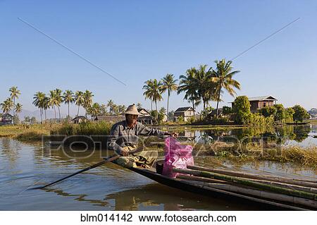 Stock Image - Burmese man rowing traditional boat. Fotosearch