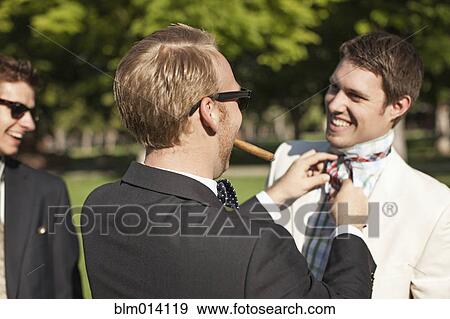 Caucasian man fixing friend's tie View Large Photo Image Stock Photo - Caucasian man fixing friend's tie. Fotosearch