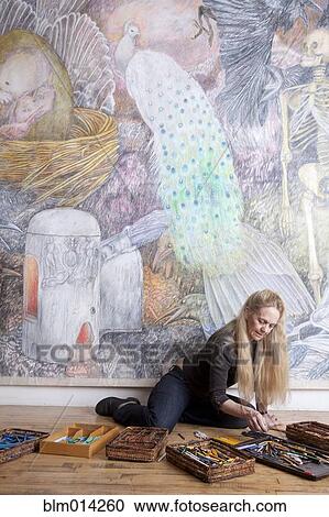Stock Image - Caucasian woman drawing mural on wall. Fotosearch
