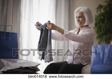 Stock Photo - Caucasian woman holding new sweater. Fotosearch
