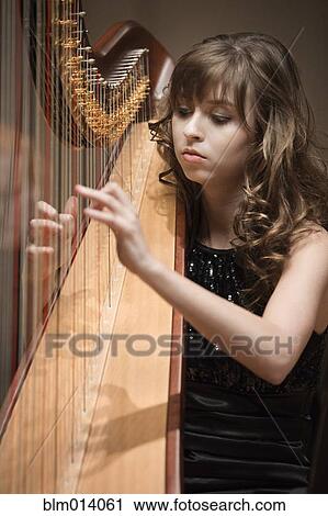 Stock Image - Caucasian woman playing harp. Fotosearch