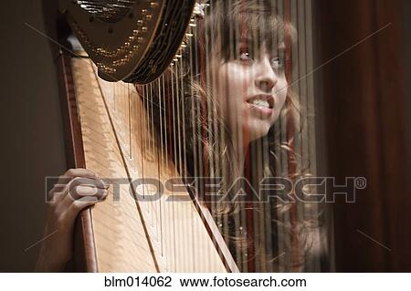 Stock Image - Caucasian woman playing harp. Fotosearch