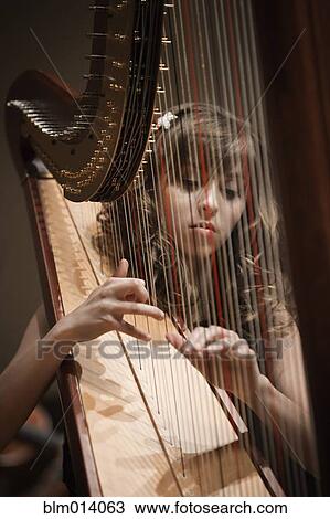Stock Image - Caucasian woman playing harp. Fotosearch