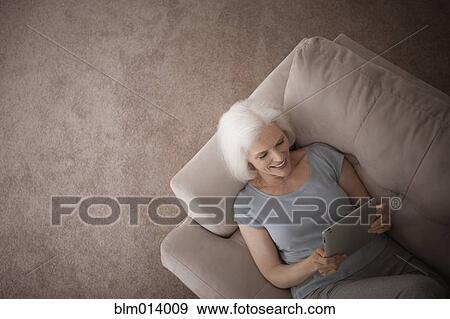 Caucasian woman using digital tablet on sofa View Large Photo Image Stock Photo - Caucasian woman using digital tablet on sofa. Fotosearch