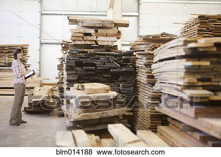 Stock Photo - Caucasian worker checking lumber in warehouse. Fotosearch