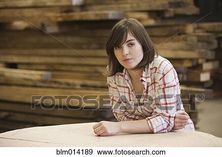 Stock Photo - Caucasian worker leaning on lumber in factory. Fotosearch