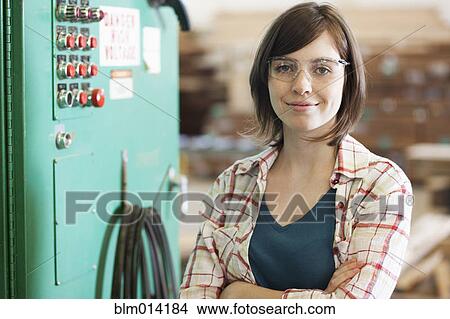 Picture - Caucasian worker standing next to machine in factory. Fotosearch