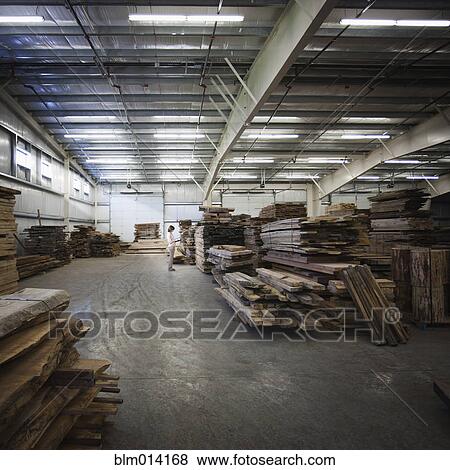 Stock Photo - Caucasian worker with lumber in warehouse. Fotosearch
