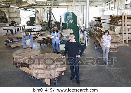 Stock Photo - Co-workers standing together in lumber factory. Fotosearch