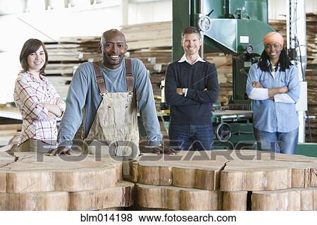Stock Photo - Co-workers standing together in lumber factory. Fotosearch