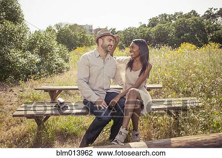 Stock Image - Couple sitting on bench. Fotosearch