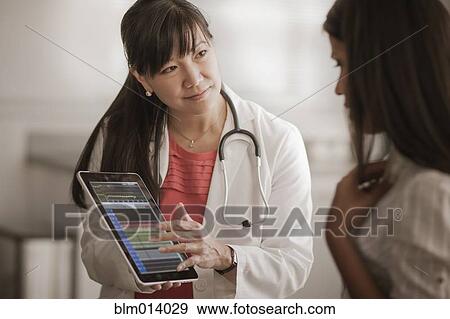 Stock Photo - Doctor showing digital tablet to patient. Fotosearch