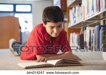 Stock Photo - Hispanic boy reading book in library. Fotosearch