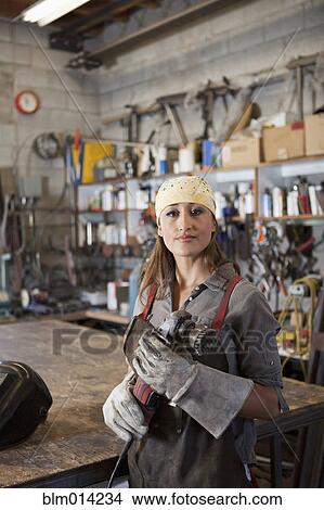 Picture - Hispanic factory worker holding metal fabricator. Fotosearch