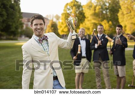 Stock Photo - Man holding croquet trophy on lawn. Fotosearch