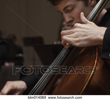 Stock Photo - Man playing cello in orchestra. Fotosearch