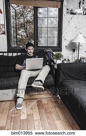 Mixed race man sitting on sofa with laptop View Large Photo Image Stock Photography - Mixed race man sitting on sofa with laptop. Fotosearch