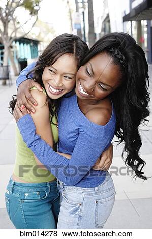 Smiling friends standing together hugging View Large Photo Image Stock Photo - Smiling friends standing together hugging. Fotosearch