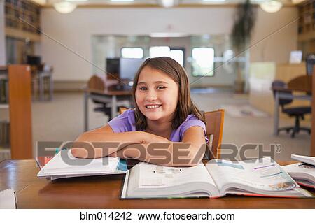 Stock Image - Smiling mixed race girl studying in library. Fotosearch