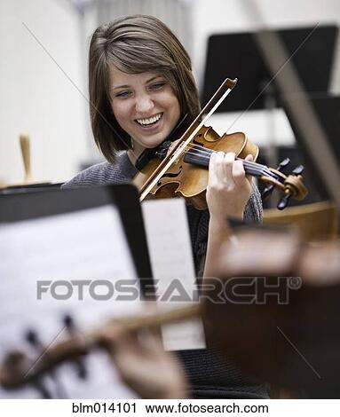 Stock Image - Woman playing violin in orchestra. Fotosearch