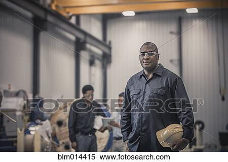 Stock Photography - African American worker standing in factory. Fotosearch