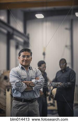 Stock Image - Asian worker standing in factory. Fotosearch