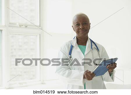 Stock Photo - Black doctor standing with digital tablet. Fotosearch