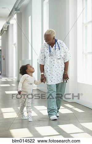 Black nurse walking in corridor with girl View Large Photo Image Stock Image - Black nurse walking in corridor with girl. Fotosearch