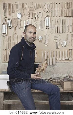 Stock Image - Carpenter holding wood in workshop. Fotosearch
