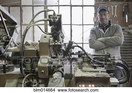 Picture - Carpenter standing near woodshop machinery. Fotosearch