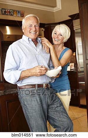 Stock Image - Caucasian couple standing in kitchen. Fotosearch