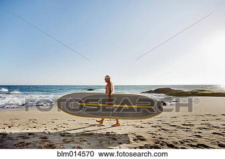 Caucasian man carrying paddleboard View Large Photo Image Stock Image - Caucasian man carrying paddleboard. Fotosearch